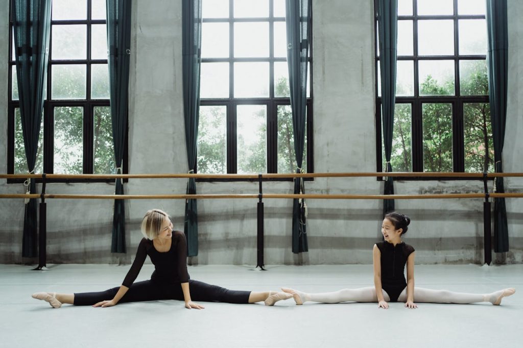 Crafting Captivating Headlines: Your awesome post title goes here Full body of smiling Asian teacher with pupil doing splits in ballet studio with barre