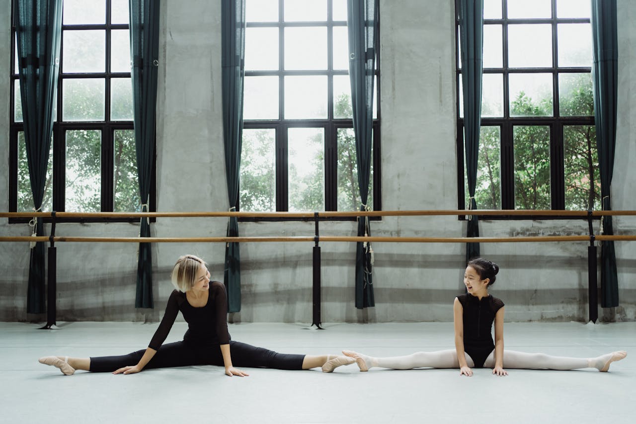 Crafting Captivating Headlines: Your awesome post title goes here Full body of smiling Asian teacher with pupil doing splits in ballet studio with barre